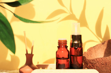 Aromatherapy & beauty spa set, essential oils, plant leaves shadows yellow sunny background. Relaxing tropical body care, summer scents. 