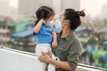 Asian mother and little young daughter wearing a face prevent the spread of the Covid-19, Covic 19 virus protection concept in Thailand.