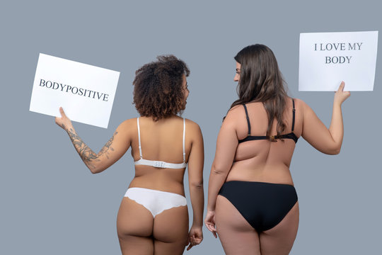 Two women of different physique in underwear standing with their backs.