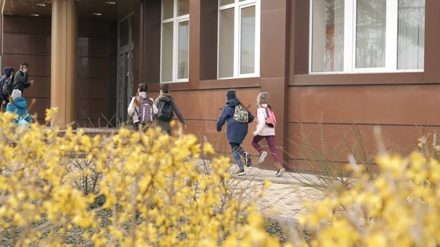 Children students in medical masks leave the school