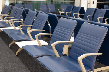 Row of empty blue chairs in an airport waiting area.