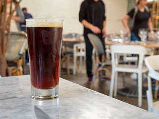 Dark stout beer sitting on table in restaurant with diners getting seated