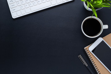 Workplace in office with black desk. Top view from above of keyboard with notebook and phone. Space for modern creative work of designer. Flat lay with blank copy space. Business and finance concept.