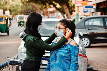  Indian female helping each other by wearing masks to prevent themselves from the corona virus Pandemic