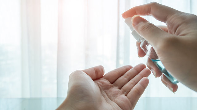 A female spraying  an antibacterial sanitizer spray by her right hand on her left hand for killing disease, bacteria, virus and Coronavirus or Covid-19. Dispenser infection control concept. 