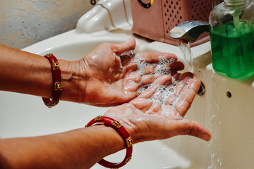 Closeup shot of Hands of an Indian female wearing bangles washing her hands after applying hand sanitizer