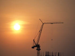 Silhouette tower crane in building construction site on Sunset Background.