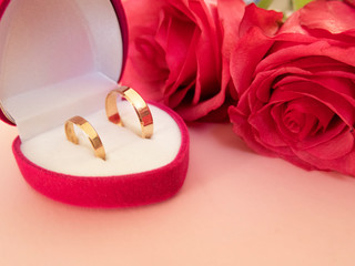 Wedding celebration with pink rose bouquet, gold wedding rings in the pink boxe, isolated on pink background.