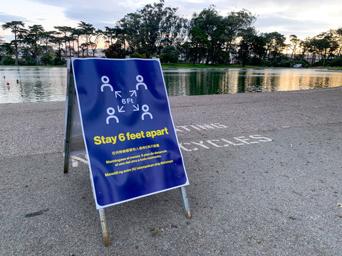Coronavirus COVID-19 social distancing signboard warning people to stay six feet apart in front of lake