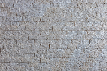 Uniform, small gray tile on the wall. Textures, backgrounds homogeneous gray stone on the wall of a room interior.