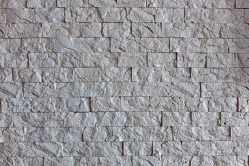 Uniform, small gray tile on the wall. Textures, backgrounds homogeneous gray stone on the wall of a room interior.