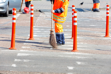 A team of janitors sweeping the street on a sunny day.
