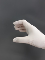 Closeup female hand with white disposable latex gloves in holding gesture, selective focus.