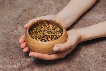 Woman holds in a bowl with tea buds