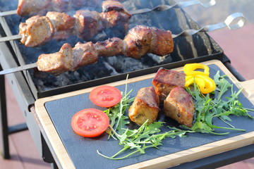The pieces of fried on a charcoal meat on the background of cooking process.