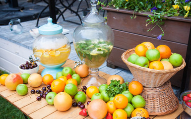 Lemonade and mojito jar with assorted fruits, apples, oranges, grape and berries on wooden table.