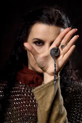 A dark-haired woman with a dirk, a Scandinavian warrior in a chain mail against a dark background
