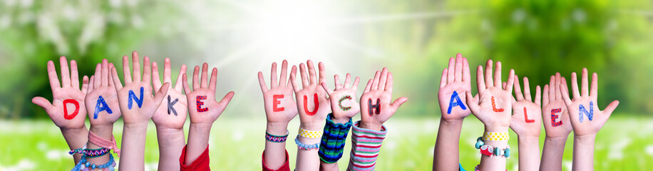 Kids Hands Holding Colorful German Word Danke Euch Allen Means Thank You All. Sunny Green Grass Meadow As Background - obrazy, fototapety, plakaty