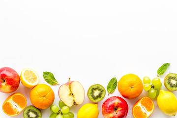 Oranges, lemon, apple, kiwi and grape - healthy food concept with fruits - on white background top-down frame copy space