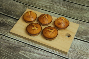 Five golden pies on a wooden board on a wooden table from boards.