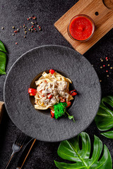 Italian, European cuisine. Pasta with mushrooms and cheese sauce, a beautiful serving of the dish in a restaurant in a black plate. black background. copy space text