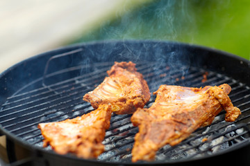 cooking, culinary and food concept - close up of barbecue meat roasting on brazier grill outdoors