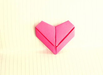 Pink paper folded into a heart shape on the background