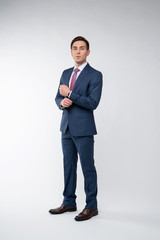 Young, handsome man in a blue suit in a white shirt with a tie on a white background in studio