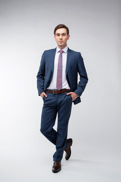 Young, Handsome Man In A Blue Suit In A White Shirt With A Tie On A White Background In Studio