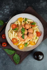 Penne pasta with meatballs tomatoes and sauce on a dark background