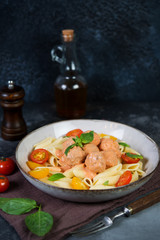 Penne pasta with meatballs tomatoes and sauce on a dark background
