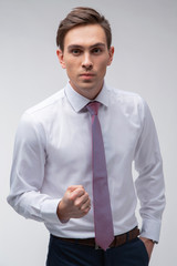 Young, handsome man in a white shirt with a tie on a white background in studio
