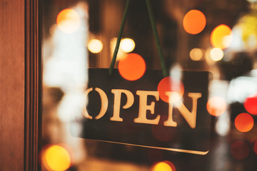 Open sign broad hanging on wood door front of cafe.