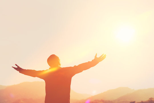 Copy space of man rise hand up on top of mountain and sunset sky abstract background.