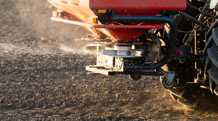 Tractor spreading artificial fertilizers in field - obrazy, fototapety, plakaty