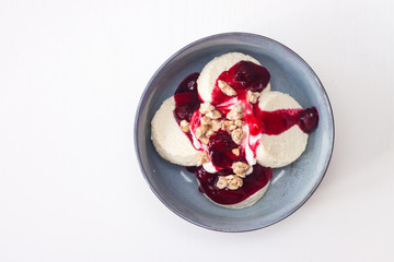 Cottage cheese pancakes or fritters with cherry sauce and chopped nuts on plain white background. Isolated. Healthy breakfast.
