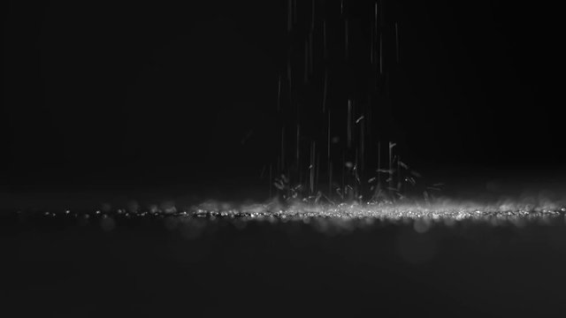 Pouring white sugar on black background in slow motion. closeup