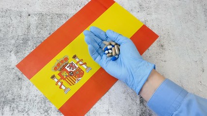 covid - 19, coronavirus concept. Hand in medical glove with pills on Spanish flag, coronavirus epidemic in Spain concept - Powered by Adobe