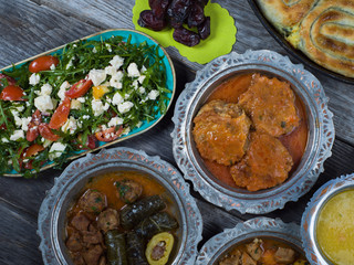 Eid Mubarak Traditional Ramadan Iftar dinner. Assorted tasty food in authentic rustic dishes on wooden table background.