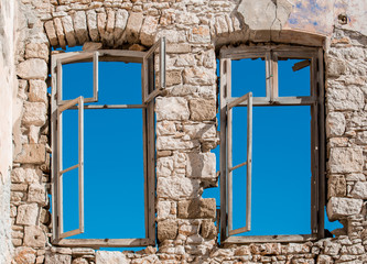 Two windows with wooden frames of a retro light brown brick wall building close up, clear blue skies window view