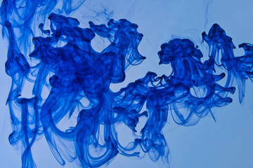 Swirl of blue dye dissolved in light blue water in motion, macro photography