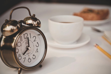 alarm clock and cup of coffee on a table