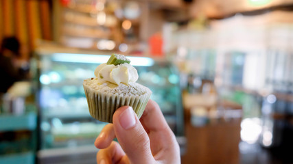 Hand holding greentea cupcake  on blurred background