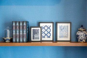 Stylish bookshelf with home decor in modern room on a blue wall © Itagaki