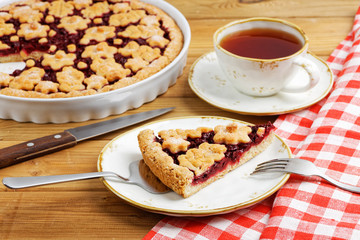 Homemade cherry pie crostata and cup of tea on wooden table. Shallow focus.