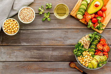 Quinoa, avocado and chickpeas in bowl in hands - balanced healthy food - on wooden table. Top view copy space