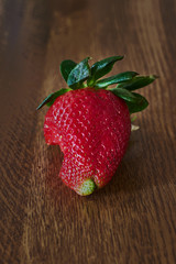 Strawberry with a bite on a wooden table