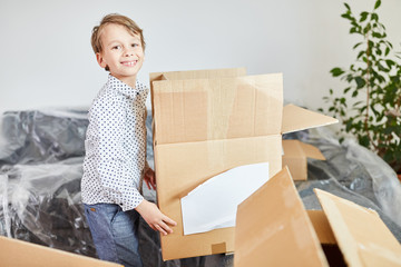 Glücklicher Junge hilft beim Packen beim Umzug