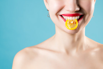 smiling girl holds a yellow condom in her teeth, the girl has red lips