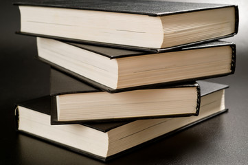Books with black covers shot on a dark background. Background for study, reading and science.